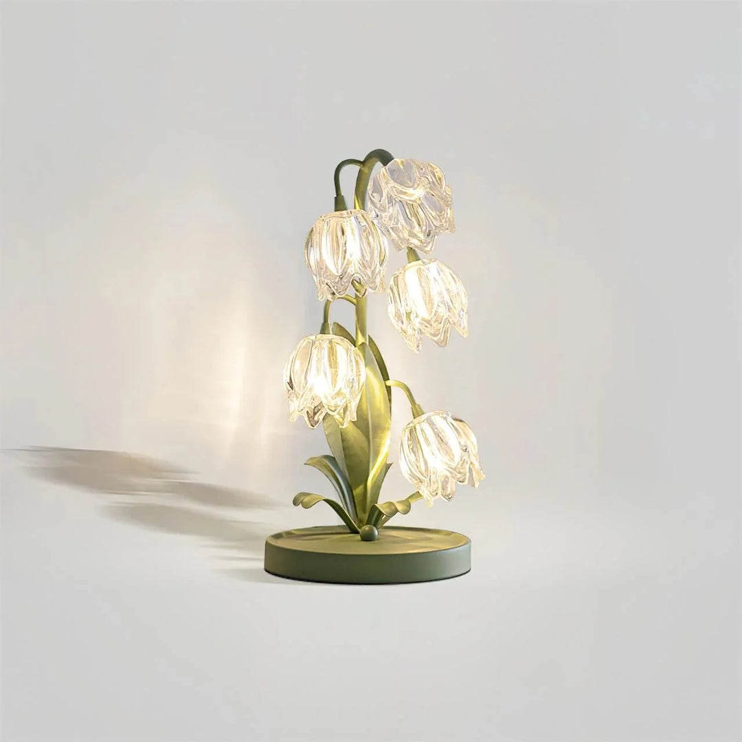 Illuminated green metal table lamp with translucent glass petal shades glowing on a light background