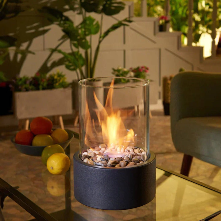 Indoor glass tabletop fireplace sitting on a glass coffee table with fruit bowls