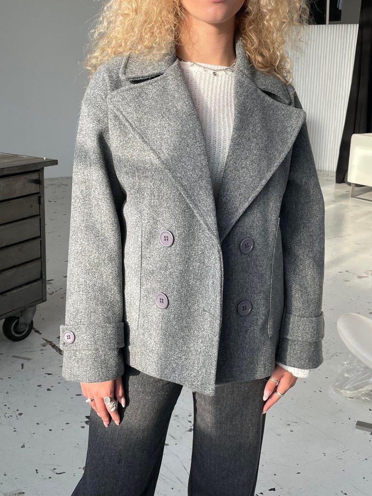 Detailed view of fabric texture and buttons on the grey winter jacket
