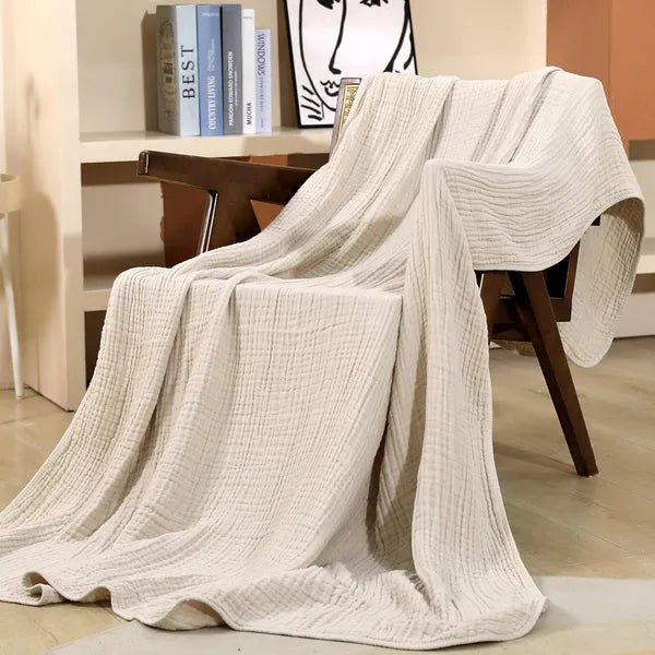 Beige muslin throw blanket draped elegantly over a wooden chair