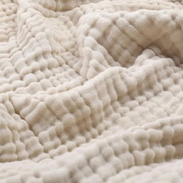 Neutral-toned lightweight blanket neatly folded on a modern accent chair