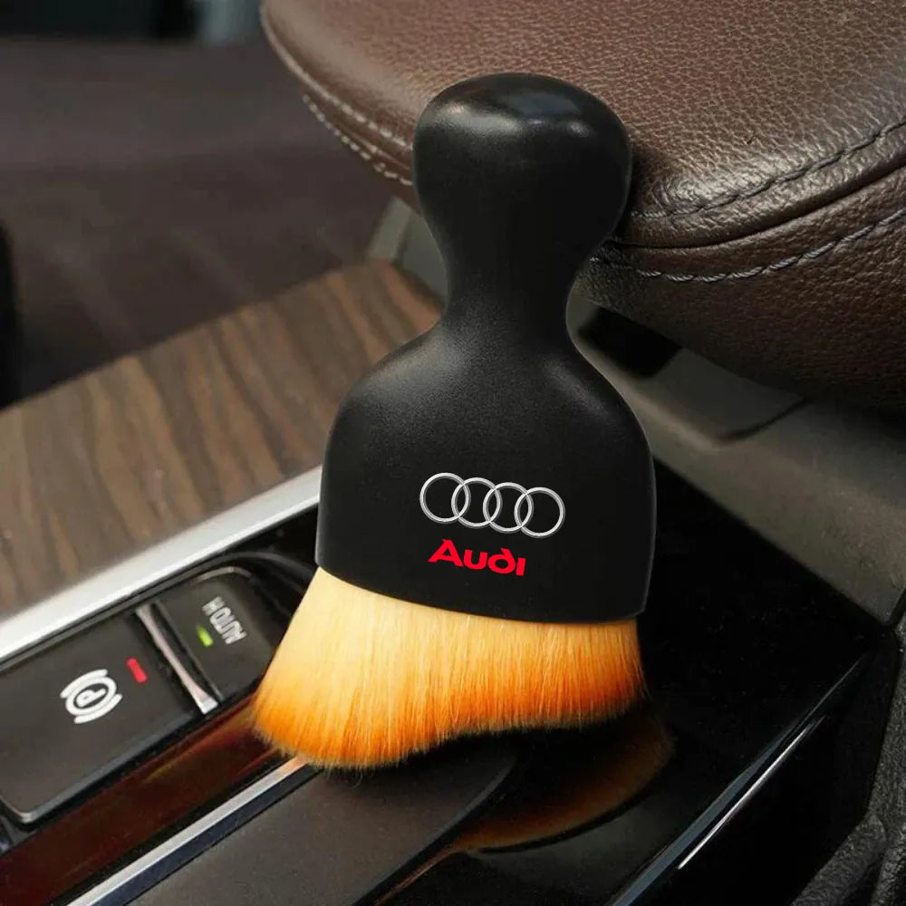Black car interior detailing brush with Audi logo resting on a console