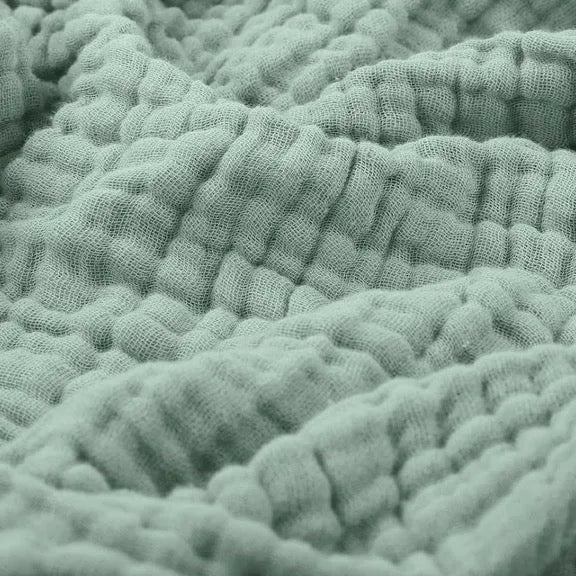 Layered muslin blanket on a made bed creating a relaxing bedroom aesthetic