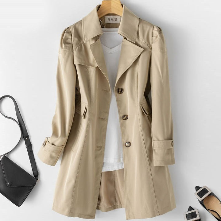 Beige Verona trench coat styled on a hanger with a black handbag nearby