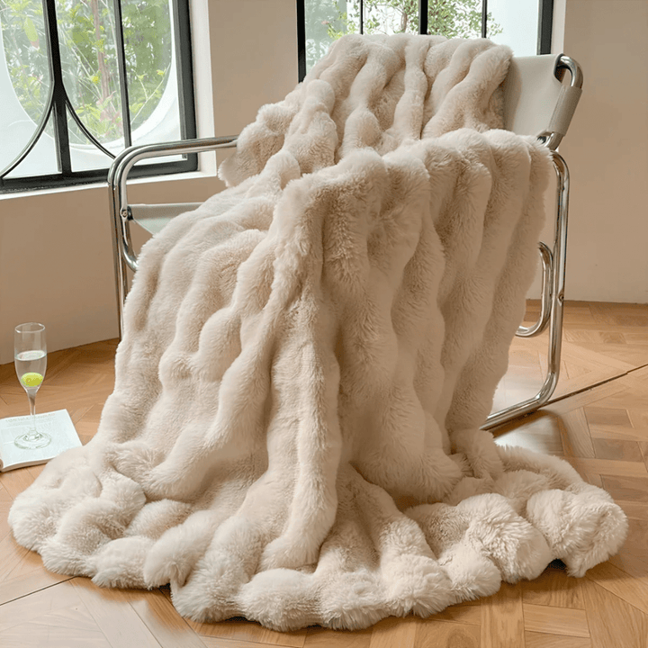 Beige ultra-soft thermal fleece blanket draped gracefully over a modern metal armchair