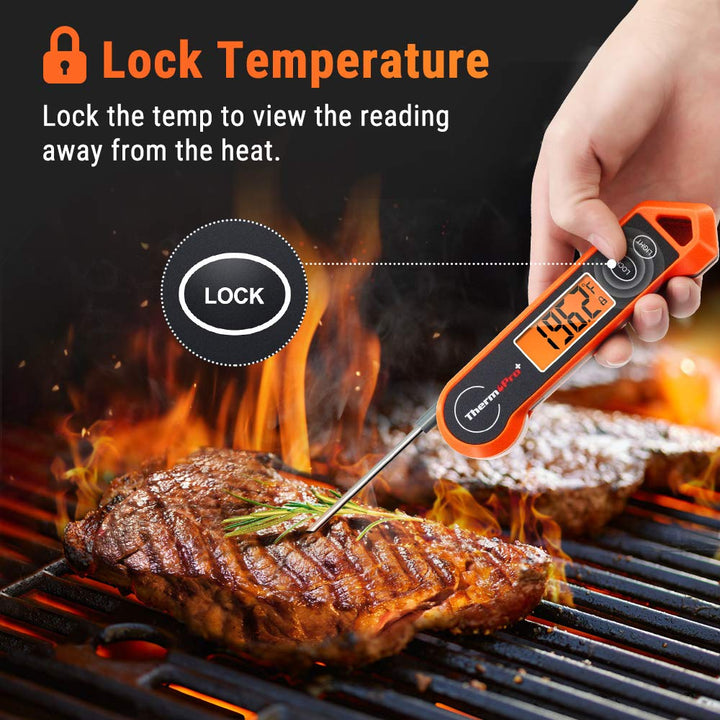 Meat thermometer measuring temperature of steak on a hot grill