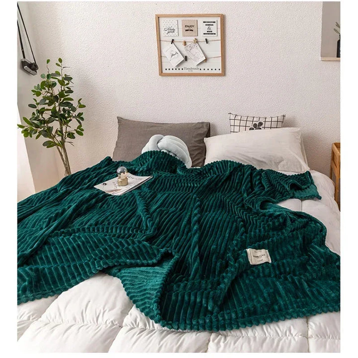 Dark green thick flannel autumn blanket draped over a bed with decorative pillows