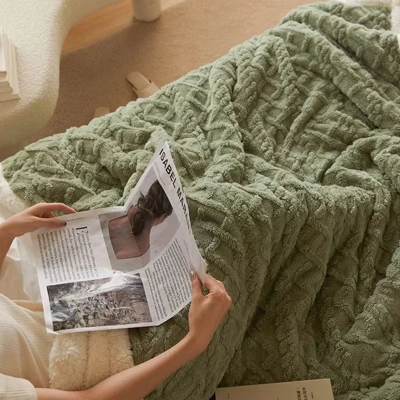 Green winter blanket resting on a bed with a book nearby