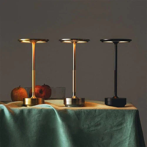 Three cordless table lamps in gold brass, silver stainless steel, and black aluminium