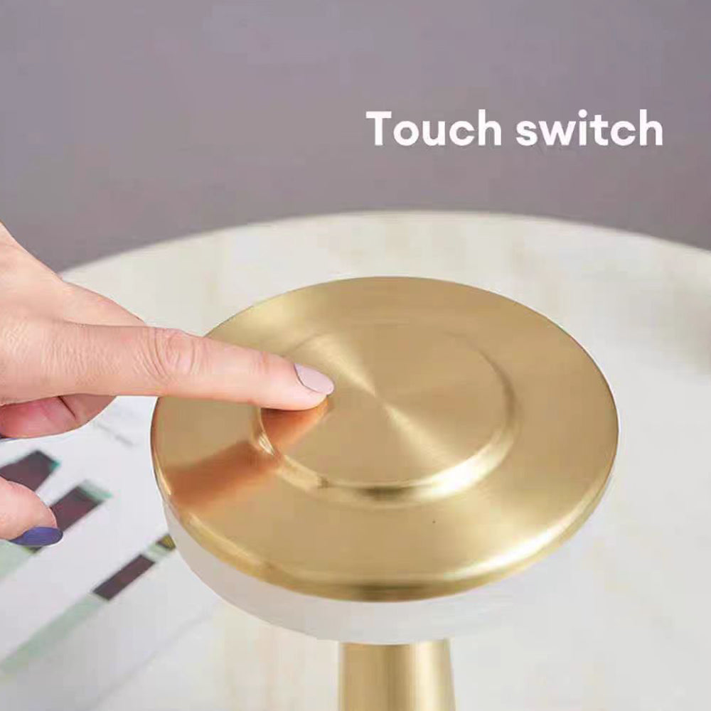 Close-up of a hand using the touch switch on top of the gold LED table lamp.