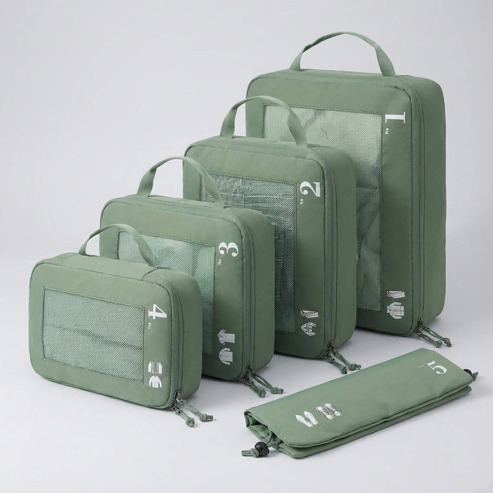 Assorted green packing cubes arranged in size order on a neutral surface