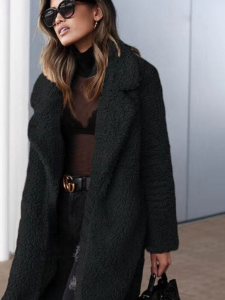 Woman wearing a black long teddy coat with sunglasses and a handbag