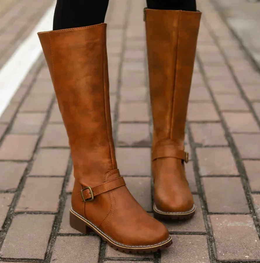 Close-up of brown women's riding boots worn on a stone walkway