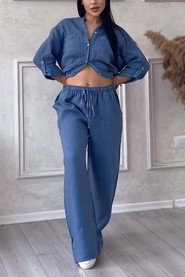Woman wearing a blue two-piece button-down blouse and wide trousers set with drawstring