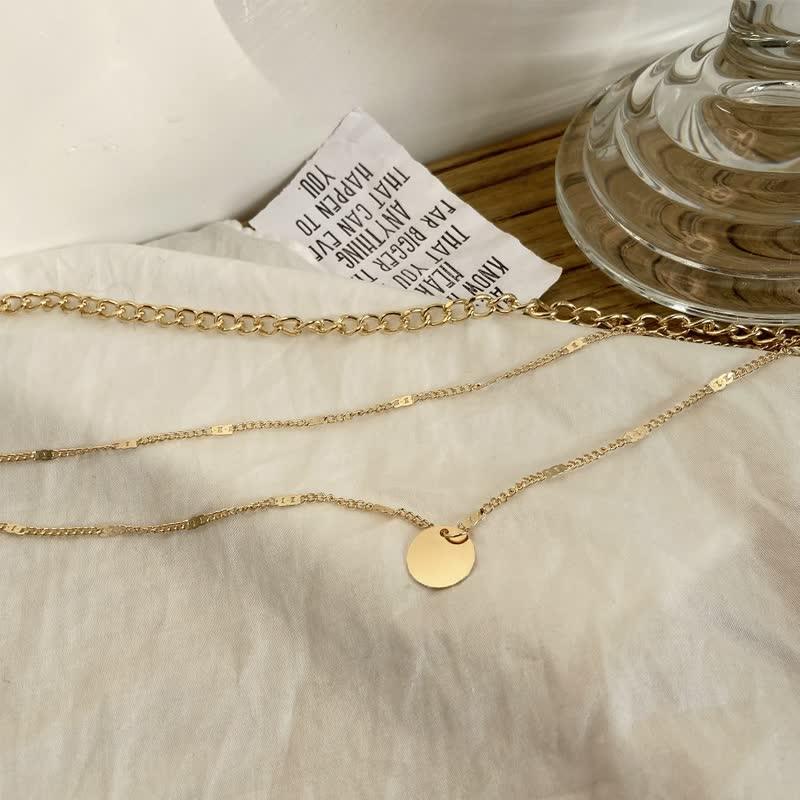 Close up shot of gold triple layered necklace set on a textured fabric surface