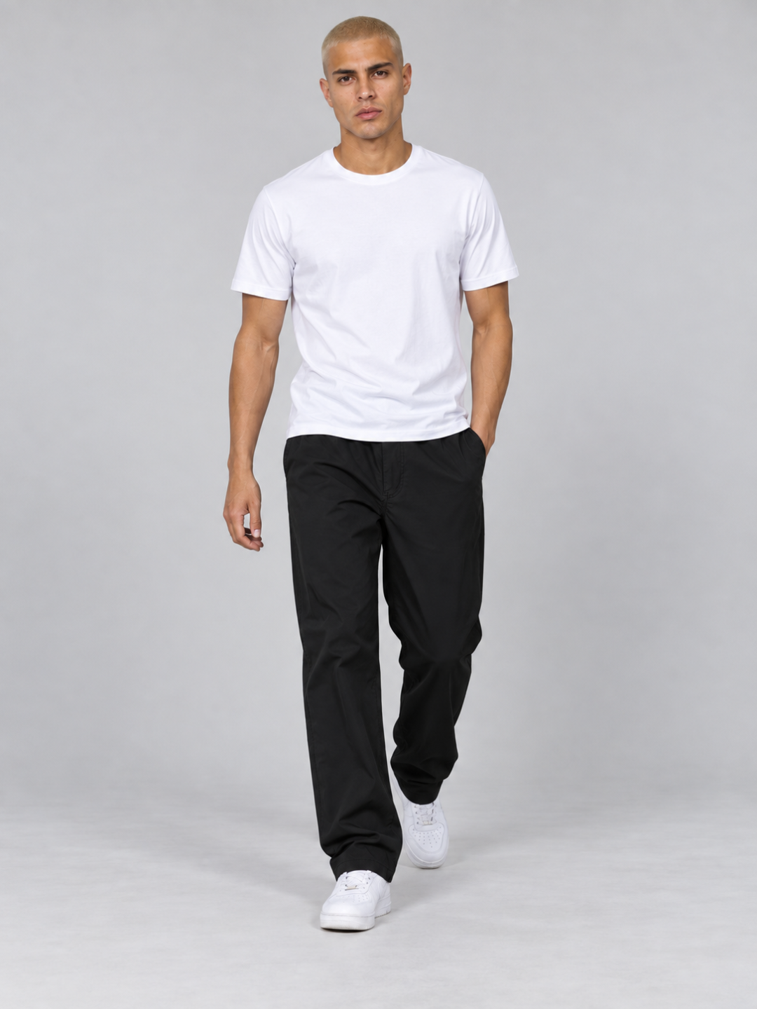 Model walking forward showcasing the relaxed fit of the black hiking trousers