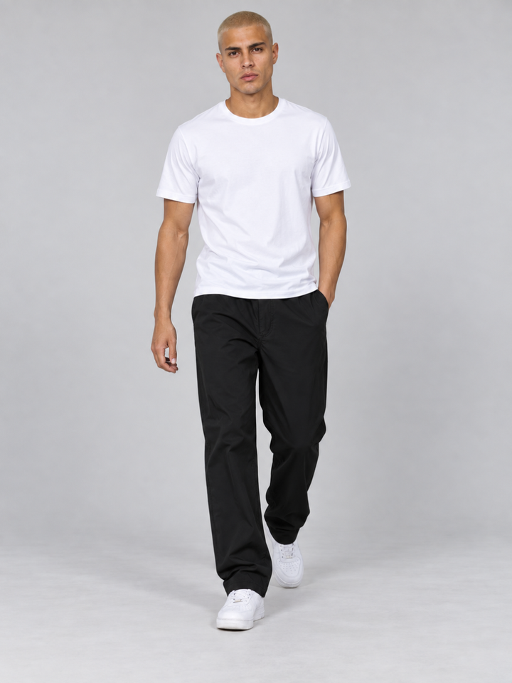 Model walking forward showcasing the relaxed fit of the black hiking trousers