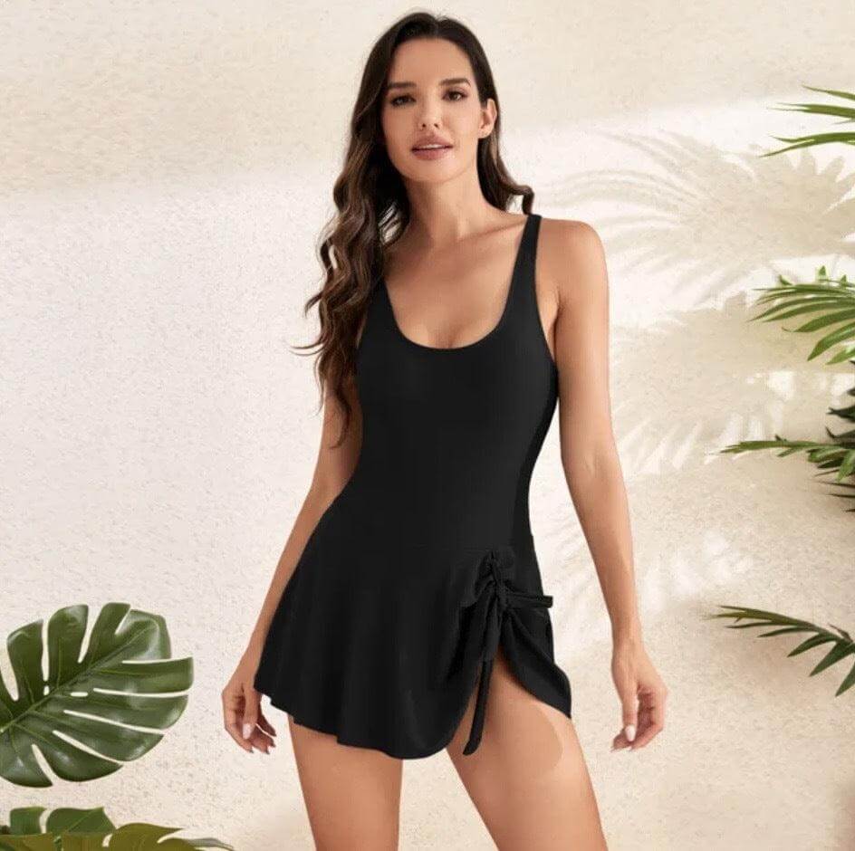 Model wearing black tummy control one-piece swimsuit with skirt overlay