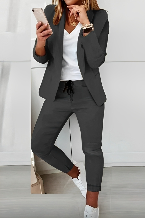 Woman wearing a dark grey two-piece blazer set in a modern setting