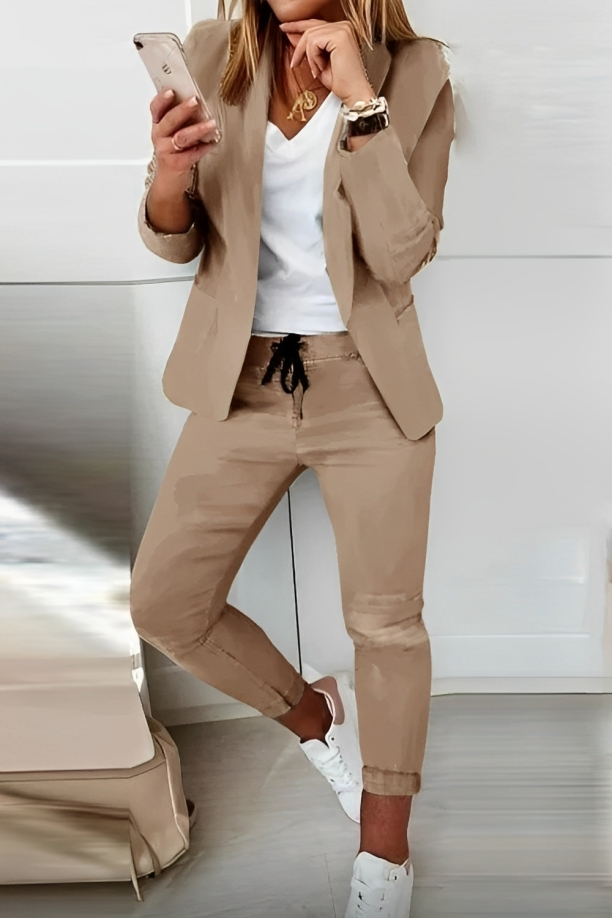 Woman wearing a khaki two-piece blazer set with smartphone