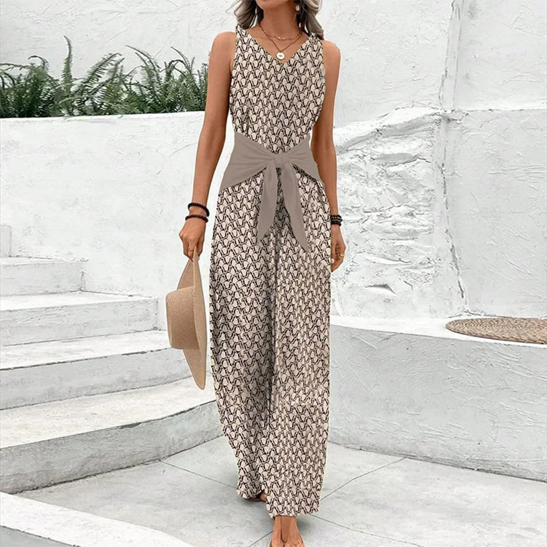 Woman wearing a beige sleeveless wide leg jumpsuit with a tie waist and V-neck