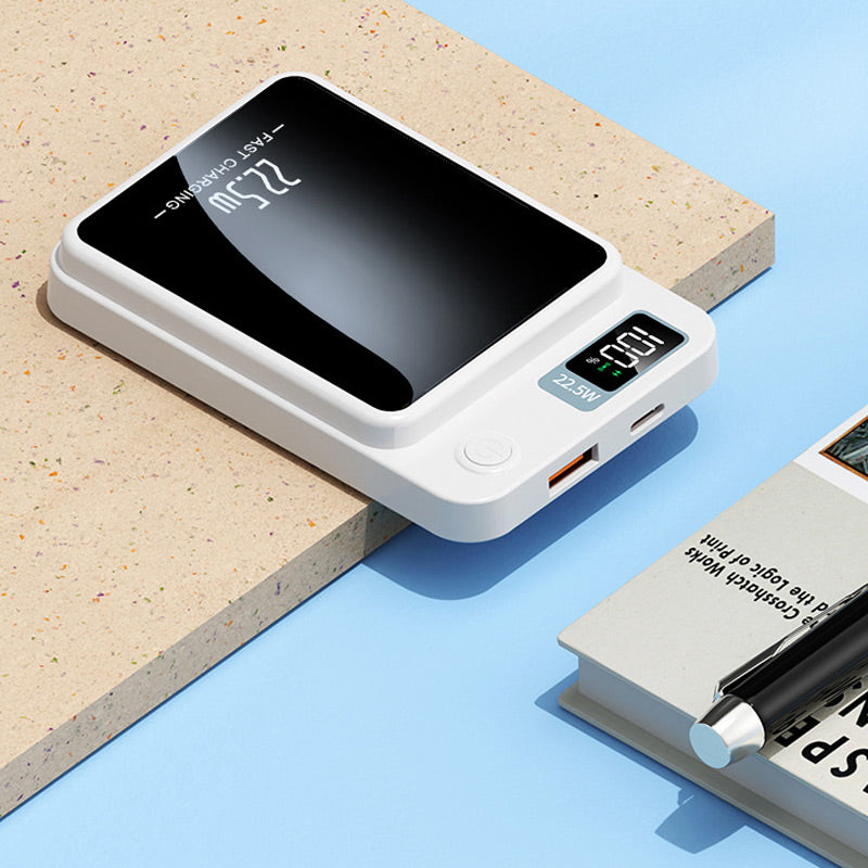White power bank resting on a surface next to a book and pen