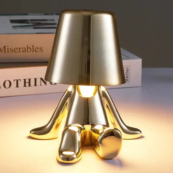 Close-up of the gold character table lamp emitting a warm glow