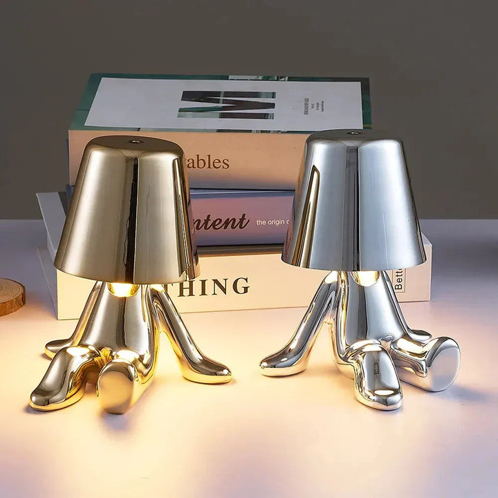 Gold and silver character table lamps sitting side by side on a desk