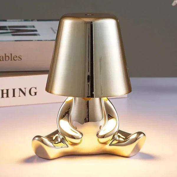 Front view of the gold decorative figurine lamp illuminating a tabletop