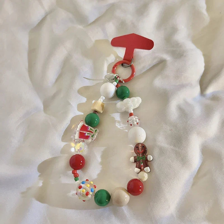 Unisex Christmas-themed beaded keychain charm resting on a soft white textile background