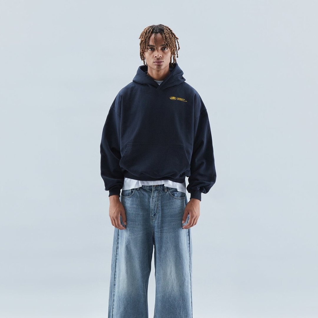 Front view of a model wearing a dark navy oversized graphic hoodie in a studio setting