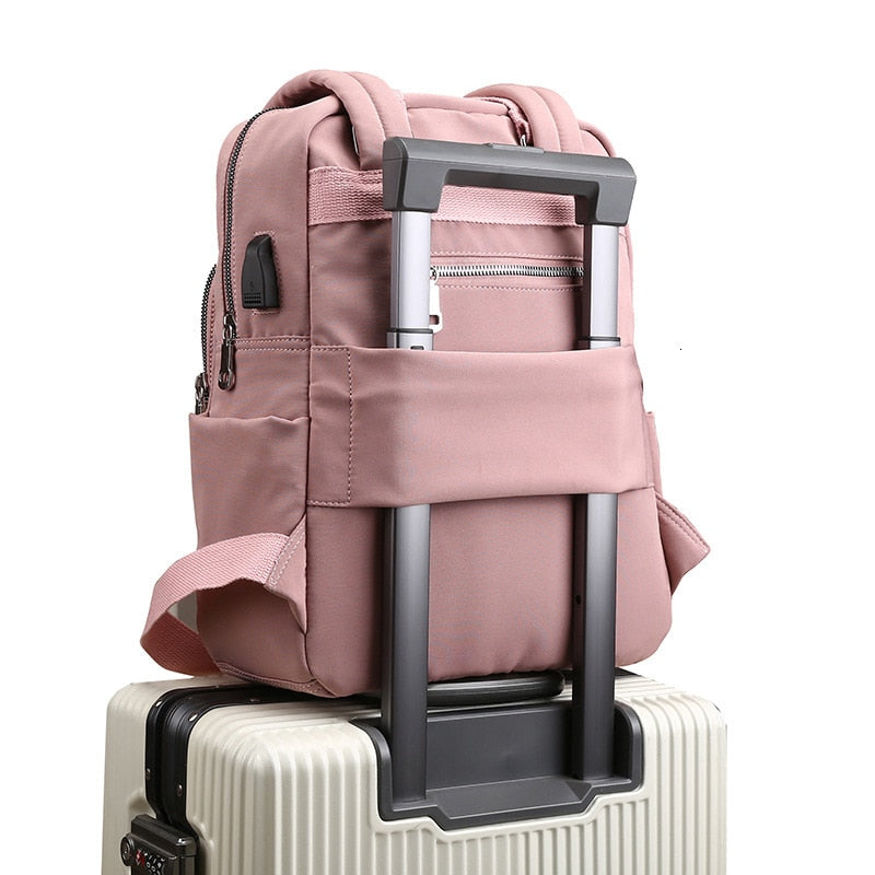 Pink anti-theft travel backpack mounted securely on a luggage handle