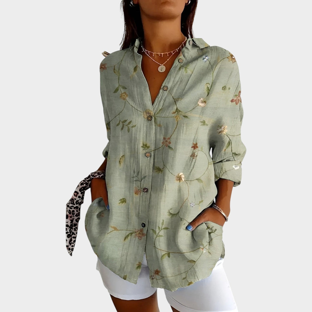 Woman wearing a green floral print button-up blouse with front pockets
