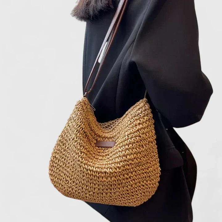 Woman wearing a khaki woven straw shoulder bag across her back
