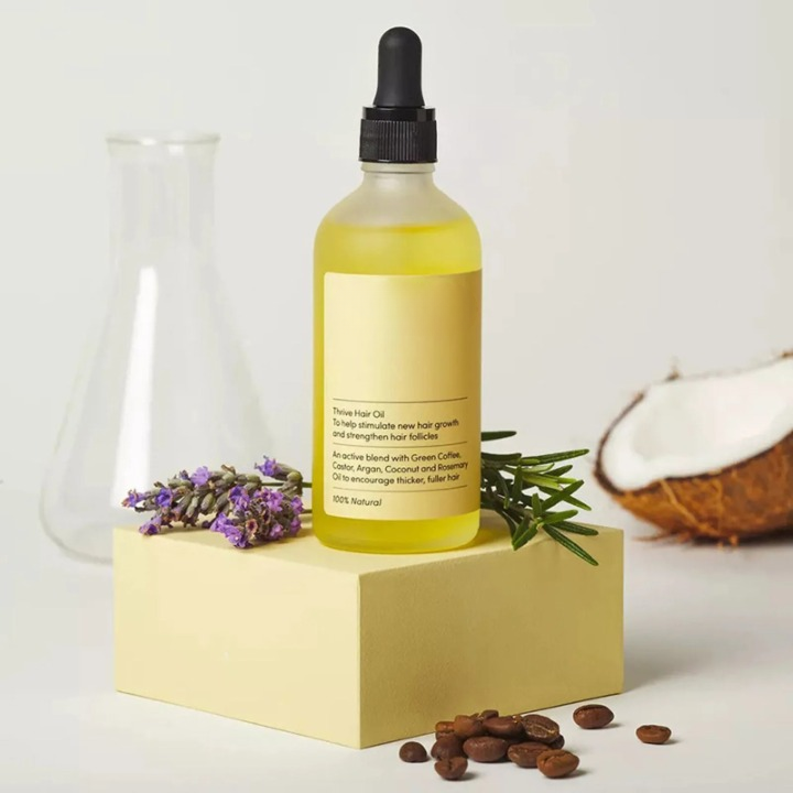 Veganic hair oil bottle displayed on a podium with natural ingredients