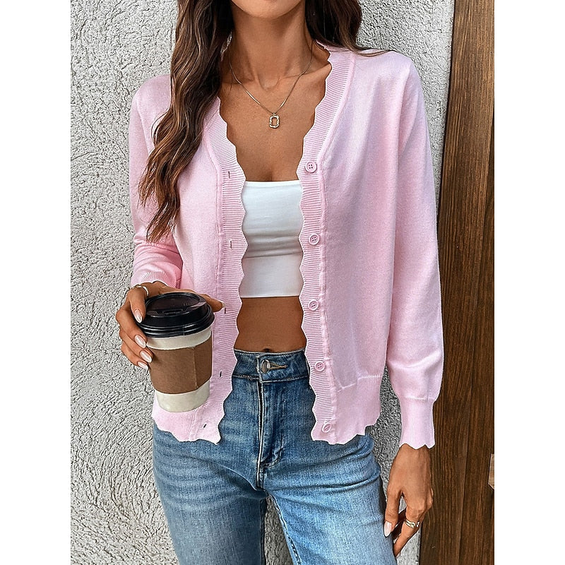 Woman wearing a pink knit cardigan with scalloped trim holding a coffee cup