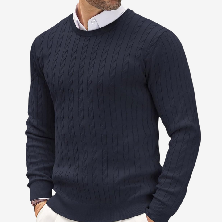 Man wearing a navy blue crew neck cable knit sweater over a white collared shirt