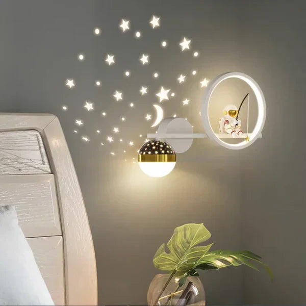 White astronaut children's wall lamp mounted on a grey bedroom wall with starry projection