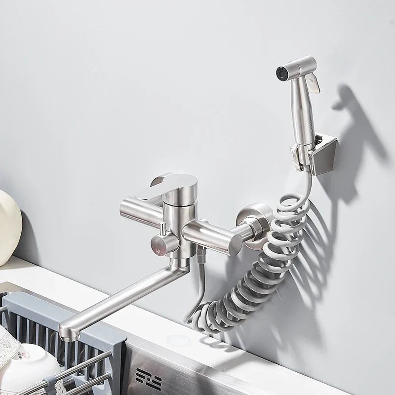 Modern stainless steel wall-mounted faucet with swivel spout and connected hand sprayer over a kitchen sink