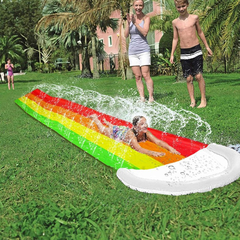Child sliding down the colorful rainbow backyard water slide
