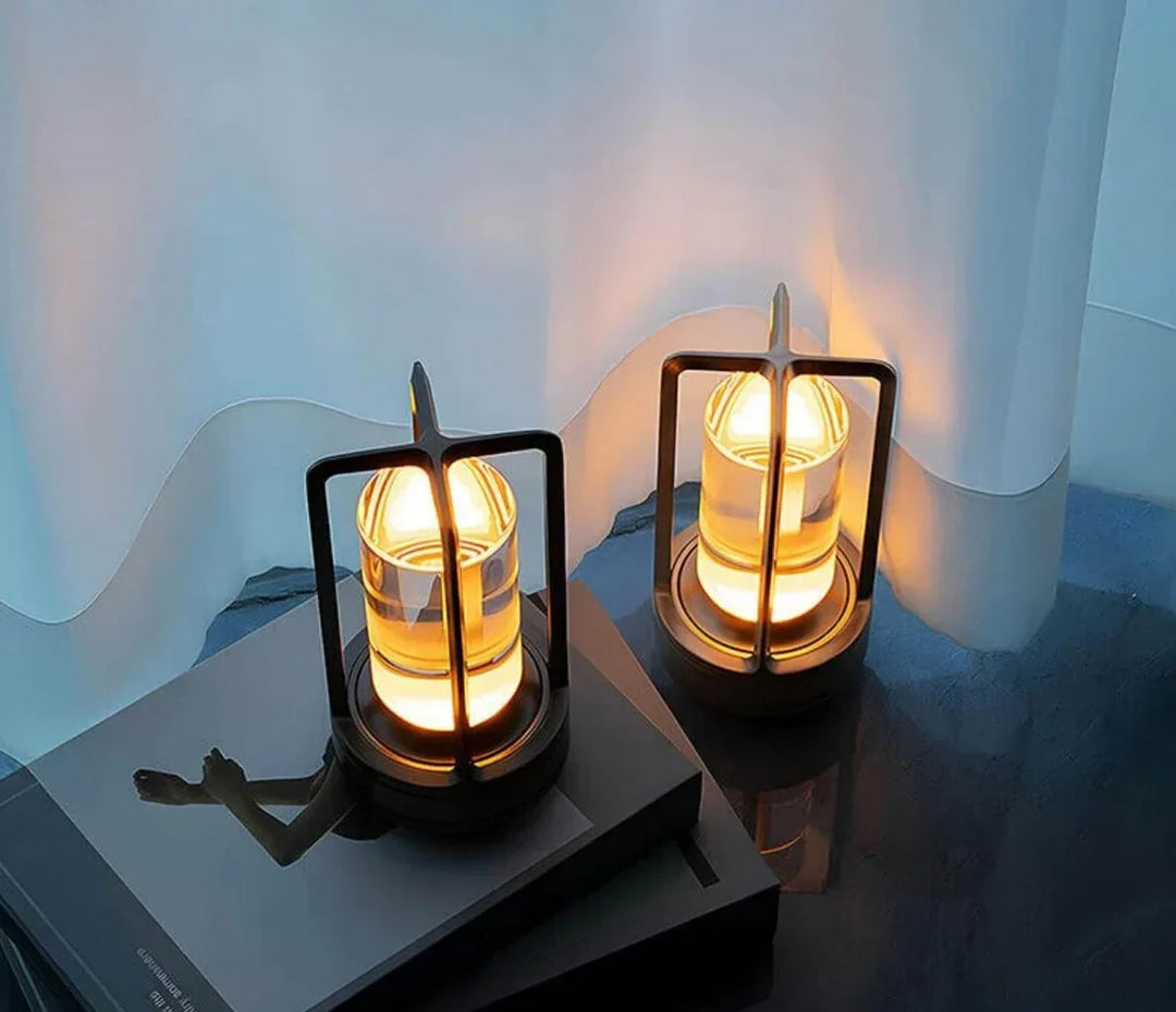 Black crystal table lamps casting a warm glow on a dark surface next to a curtain.
