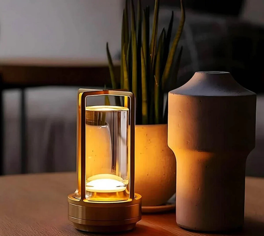 Gold waterproof portable crystal table lamp glowing on a wooden table next to a potted plant.