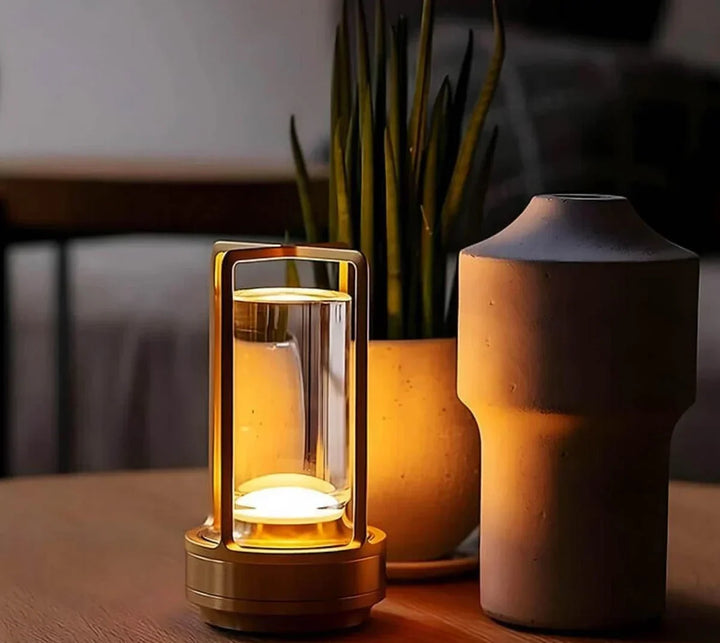 Gold waterproof portable crystal table lamp glowing on a wooden table next to a potted plant.