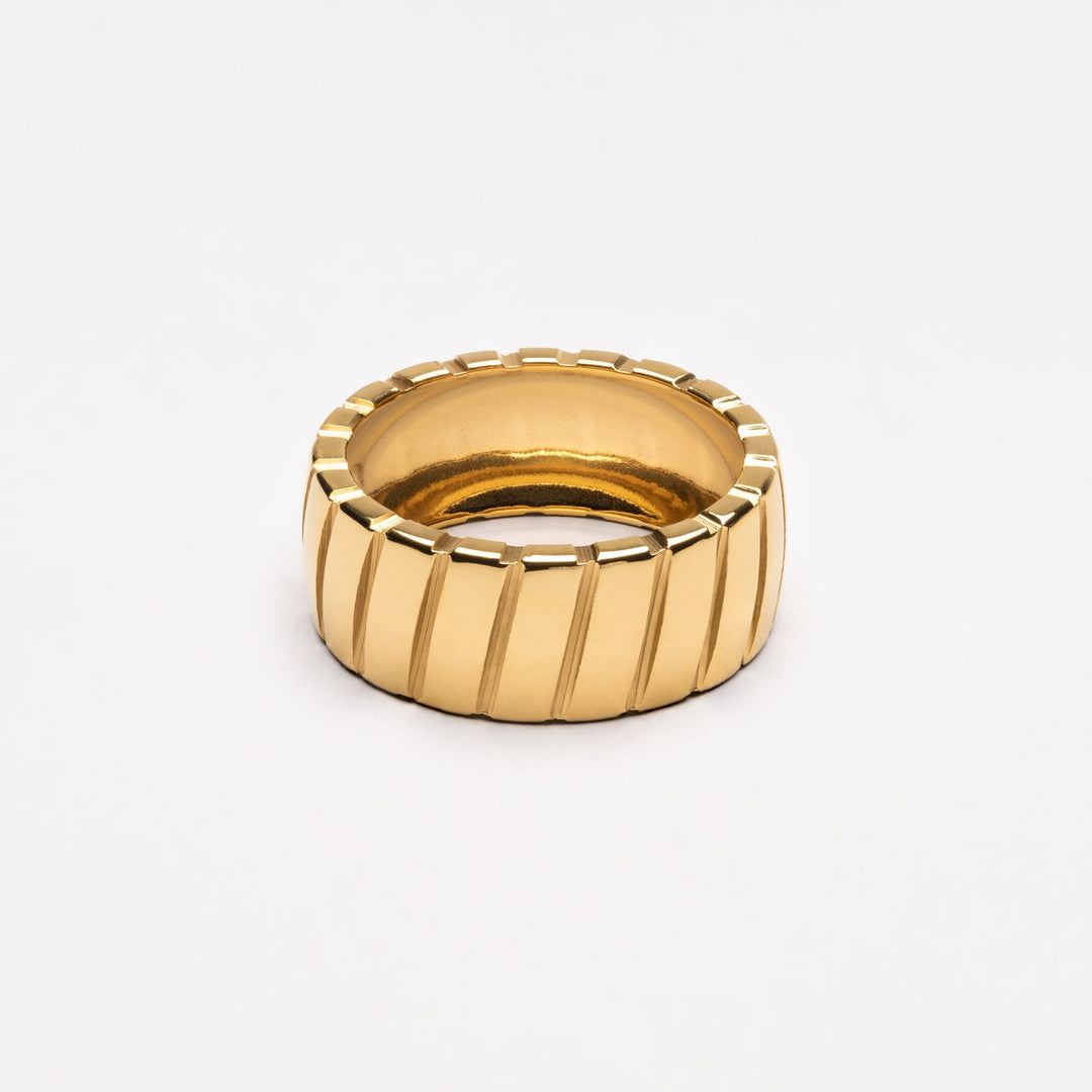 Gold statement ring with a ribbed geometric design on a clean white background