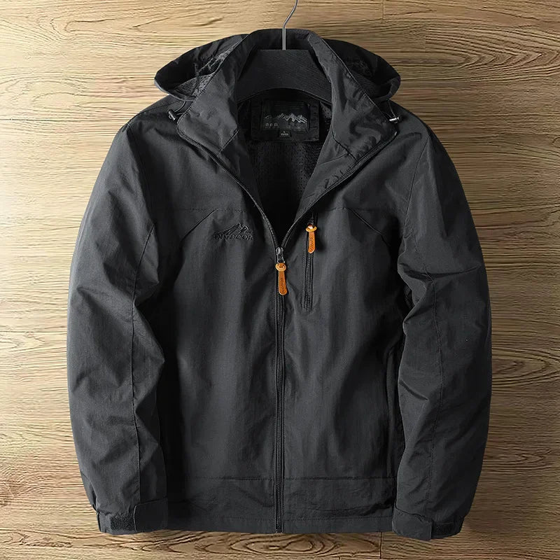 Men's black waterproof outdoor jacket hanging on a wooden background