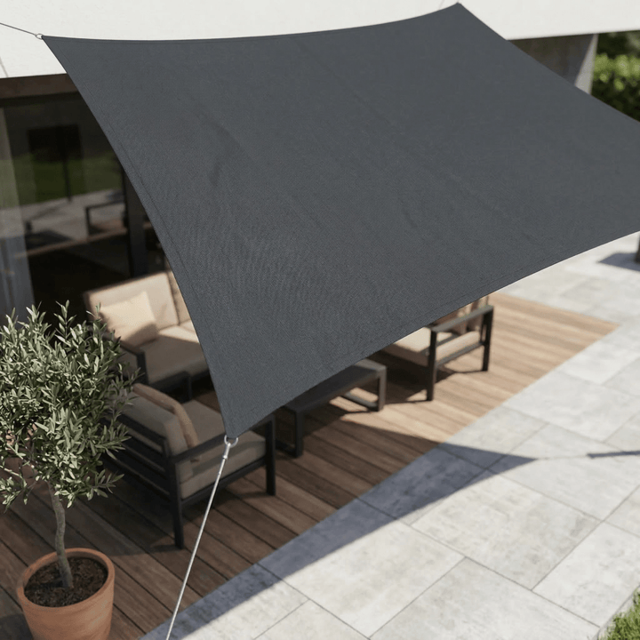 Dark gray waterproof sun sail installed over a modern patio seating area