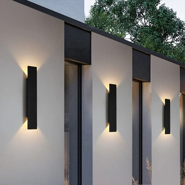 Vertical black LED outdoor wall sconces illuminating a modern home exterior