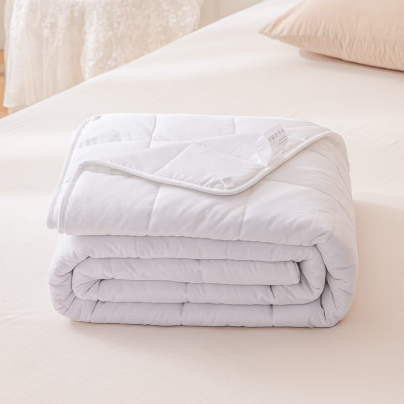 Folded white 7-layer weighted blanket resting on a neatly made bed