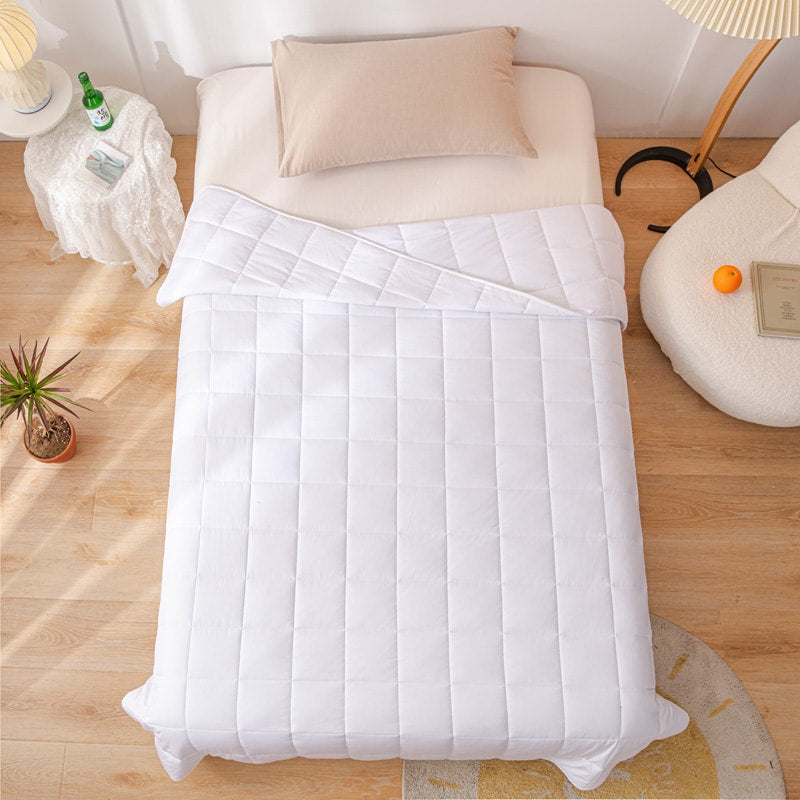 Top-down view of the white weighted blanket spread evenly across a single bed