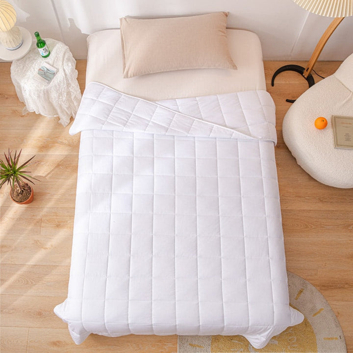 Top-down view of the white weighted blanket spread evenly across a single bed